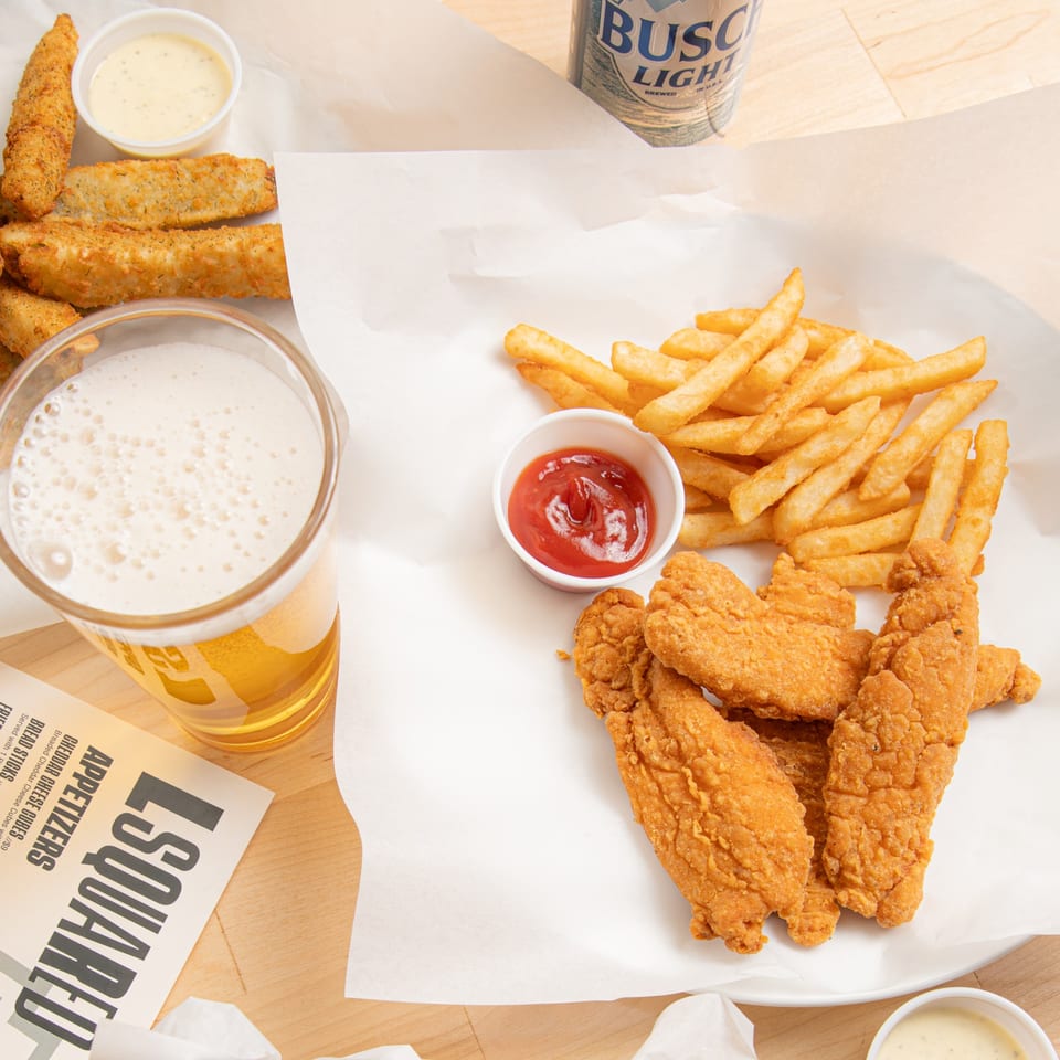 Bronko's Pizza chicken tenders, fries with ketchup, cheese sticks with dip, and a beer.