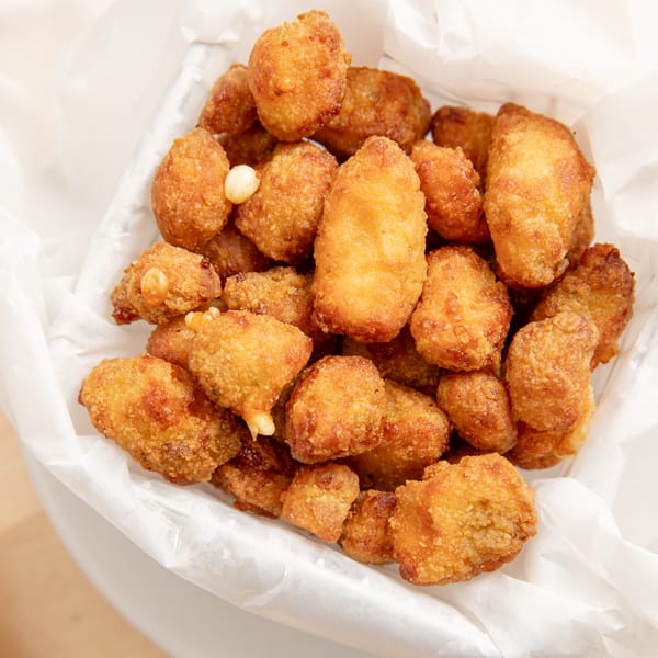 Close-up of golden-brown fried cheese curds in a white paper-lined basket from Bronko's Pizza.
